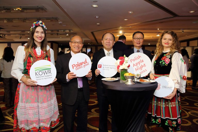 Zdjęcie przedstawia wydarzenie „Polish Apple Night”. Podczas gali przedstawiciele z Biura Polskiego w Tajpej oraz Zagranicznego Biura Handlowego Polskiej Agencji Inwestycji i Handlu w Tajpej promują polskie jabłka wśród osób reprezentujących instytucje państwowe, firmy importowe, stowarzyszenia branżowe i sieci handlowe oraz media branżowe na Tajwanie. Na stołach znajdują się polskie jabłka oraz materiały promocyjne. Zaproszeni goście pozują do zdjęć z napisem Poland tastes good.