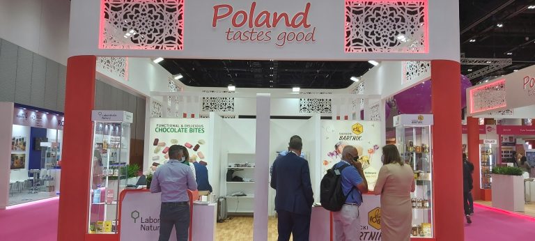 Zdjęcie przedstawia polskie stoisko narodowe. Na stoisku przeważają kolory biały i czerwony. Na fryzie stoiska dobrze widoczne logotypy Polska i Poland tastes good. Na stoisku przedstawiciele polskich firm promują swoje produkty. Stoisko cieszy się dużym zainteresowaniem zwiedzających.